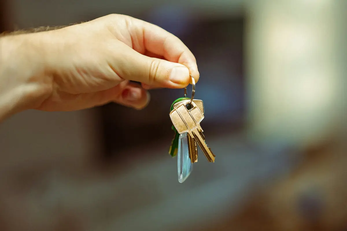 A hand holding a set of keys on a house-shaped key ring